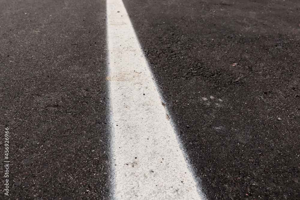 Asphalt track just made with some dirt and its texture, with a white strip painted in the center of the image Asphalt track just made with some dirt and its texture, with a white strip painted in the center of the image