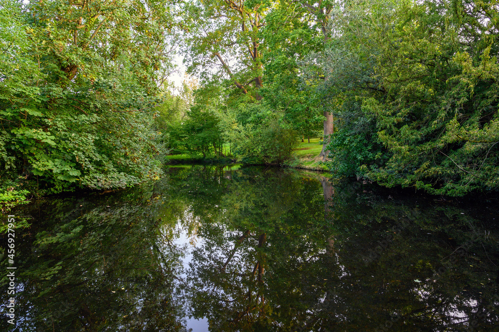 The Knoll, a small park in Hayes, Kent, UK. Reflections on the water of a small lake or pond with trees in The Knoll park. Hayes is in the Borough of Bromley in Greater London. The Knoll, a small park in Hayes, Kent, UK. Reflections on the water of a small lake or pond with trees in The Knoll park. Hayes is in the Borough of Bromley in Greater London.