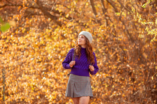 a young woman in an autumn park in a purple sweater