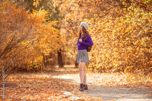 a young woman in an autumn park in a purple sweater