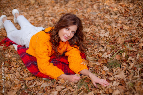 a young woman in an autumn park in an orange sweater