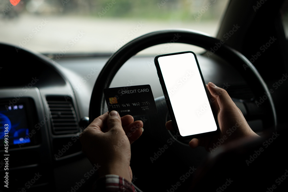 man holding white screen phone and credit card in car online shopping concept and paying bill with internet banking