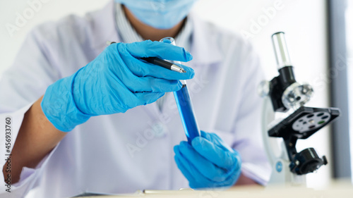 scientists researching in laboratory in white lab coat  gloves analysing  looking at test tubes sample  biotechnology concept