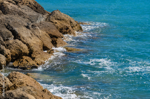 Waves of the Mediterranean Sea on a rocky coast in Cyprus near the city of Paphos in sunny summer weather. Crystal clear emerald water and rocky coastline of the Mediterranean Sea, Cyprus