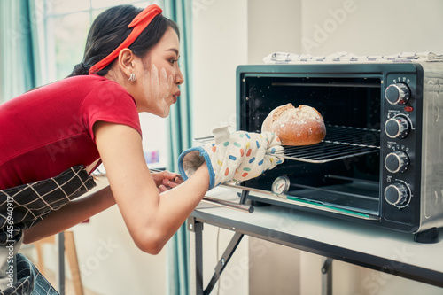 Asian female cooking bread with bakery owen in kitchen