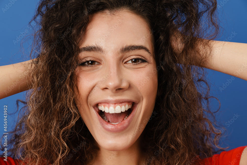 Young brunette woman with wavy hair smiling and holding her head Young brunette woman with wavy hair smiling and holding her head