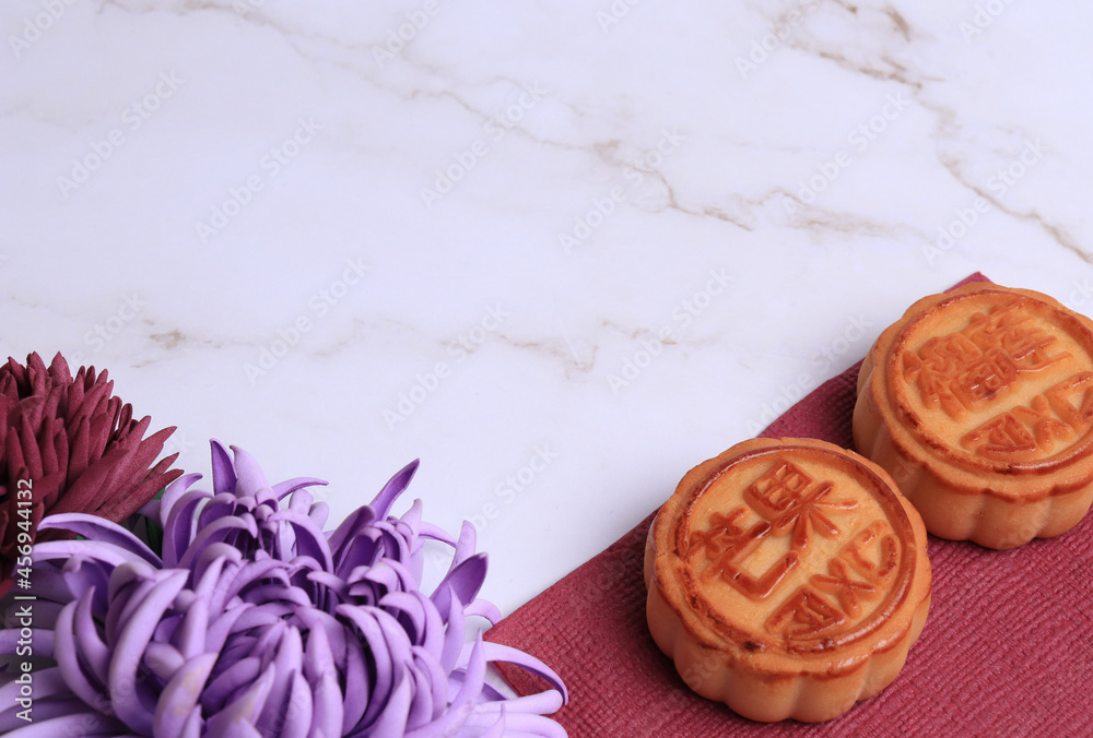 Chinese moon cake on a white marble background and bamboo mat. Asian traditional mid-autumn festival. Translation of hieroglyphs: mango pomegranate and lotus.