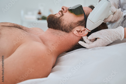 Young patient in protective eyeglasses undergoing a cosmetic procedure