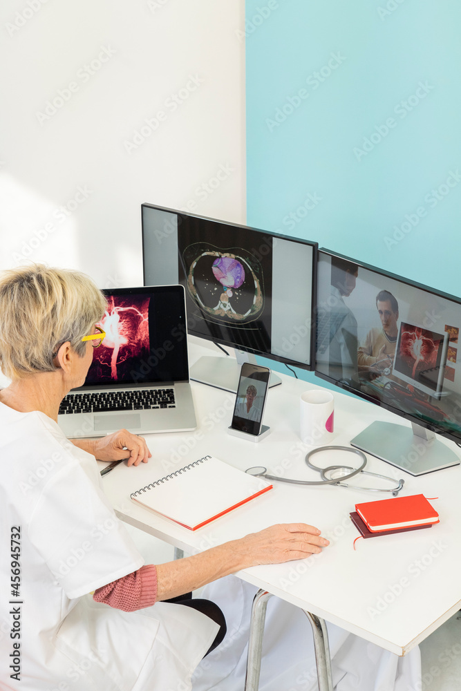 Teleconsultation between two doctors with medical images of stomachs on one of the screens.