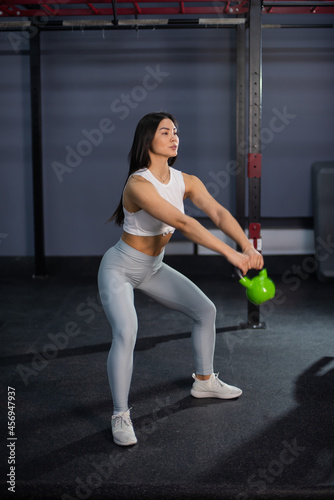 Asian woman doing exercises with dumbbells in the gym.