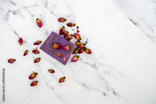 lavender scented soap bar surrounded by rose buds on marble background texture