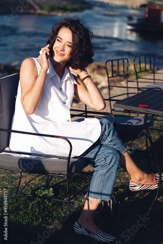 Beautiful curly hair woman talking on a phone in a cafe. Online dating concept.