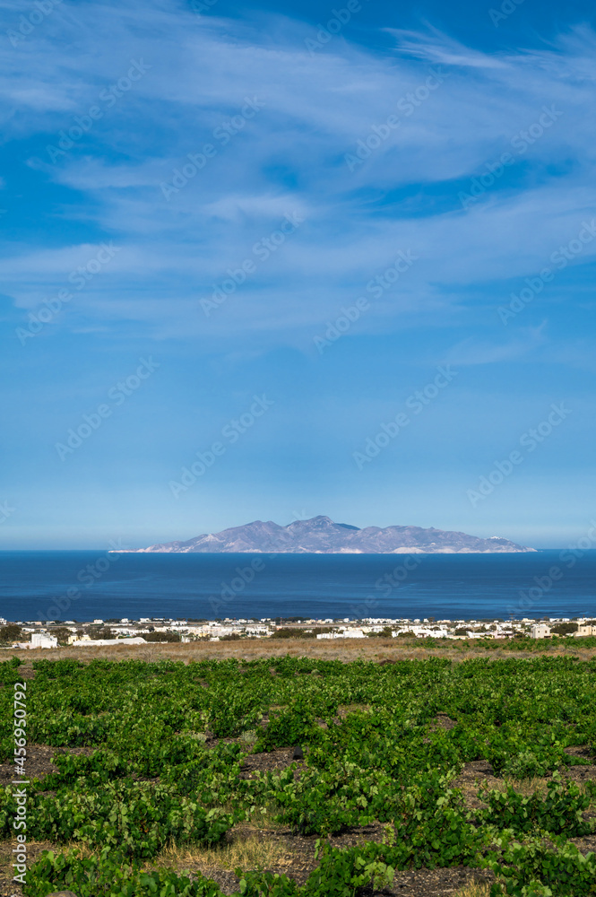 Beautiful scenic landscape of green vineyard and hill on Santorini island, Greece. Aegean sea. Summer nature. Blue cloudy sky.