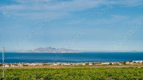 Beautiful scenic landscape of green vineyard and hill on Santorini island, Greece. Aegean sea. Summer nature. Blue cloudy sky.