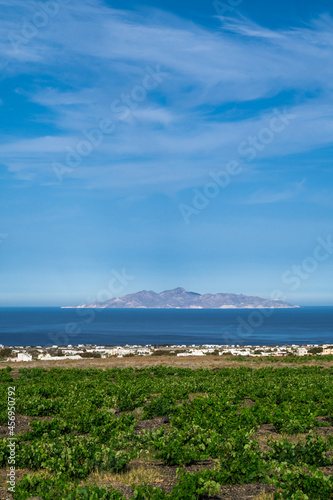 Beautiful scenic landscape of green vineyard and hill on Santorini island, Greece. Aegean sea. Summer nature. Blue cloudy sky.