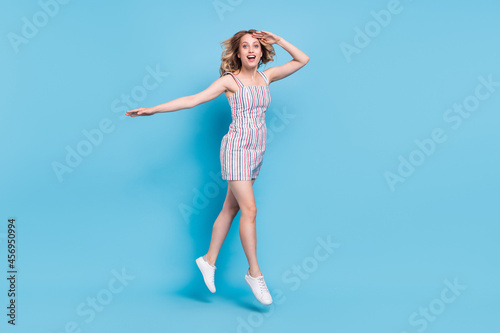 Full length body size photo woman jumping looking far hand near forehead isolated pastel blue color background