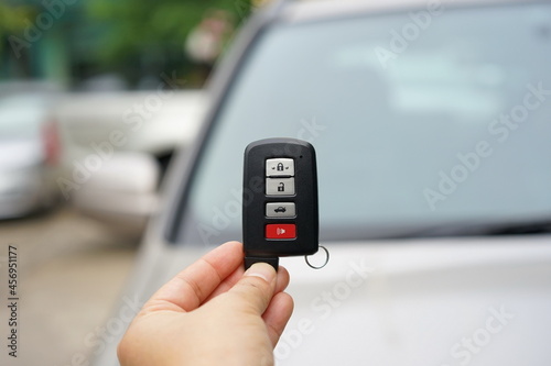 Woman hand hold black remote control car key. There was a small loop hanging and there are four buttons to lock and un-lock the car. Modern car smart key systems for cars 