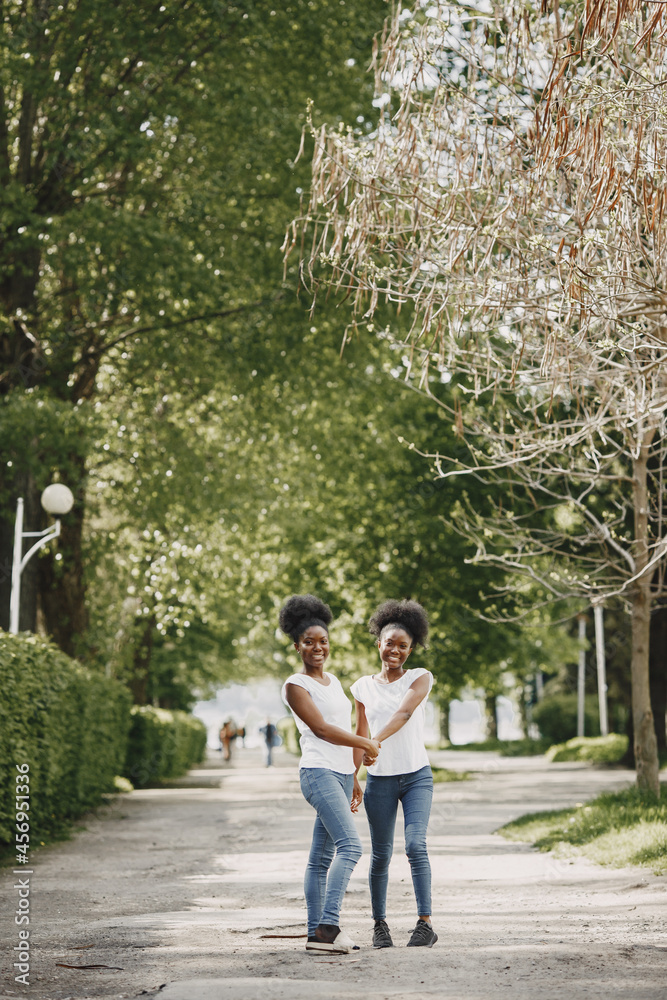 Twin sisters holding hands and walking in a park Twin sisters holding hands and walking in a park