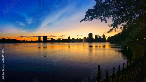 New York skyline at dawn as seen across the water of the Jackie Onassis Reservoir in Central Park, New York City.