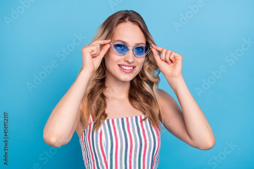 Photo portrait blonde woman wearing sunglass smiling happy isolated pastel blue color background © deagreez