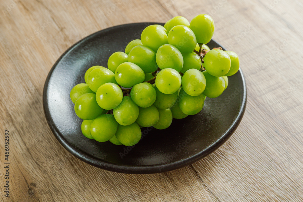 Shine muscat green grapes on a black plate Shine muscat green grapes on a black plate