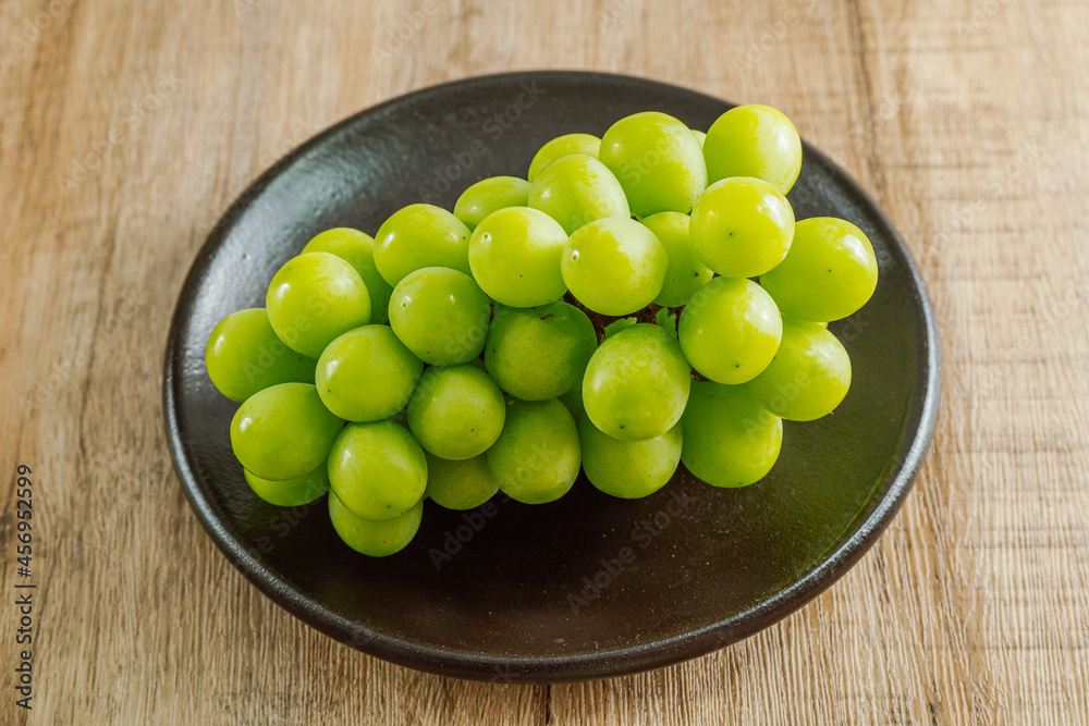 Shine muscat green grapes on a black plate Shine muscat green grapes on a black plate