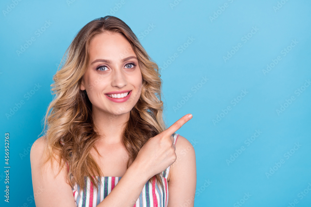 Photo of young woman happy positive smile point finger empty space advertise advise isolated over blue color background Photo of young woman happy positive smile point finger empty space advertise advise isolated over blue color background