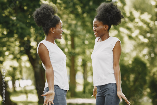 Twin sisters standing in a park and looking on each other