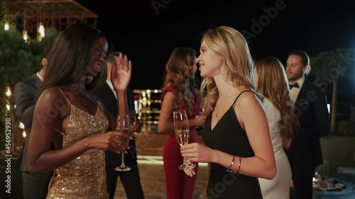 Two beautiful young women in cocktail dresses spending time on party 