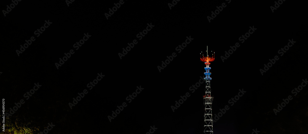 Glowing TV tower at night. Festive illuminated broadcast tower. Space for text. Long exposure.