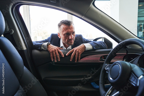 Serious person looking inside the car and frowning