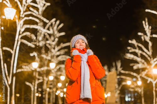 Winter holiday season. Christmas, New Year concept. Funny happy woman spend time having fun near illuminated and decorated showcase on city street.