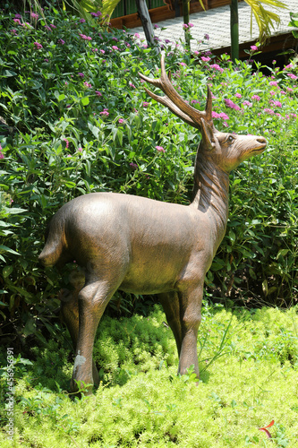 A deer statue is standing in the garden. © noomcm