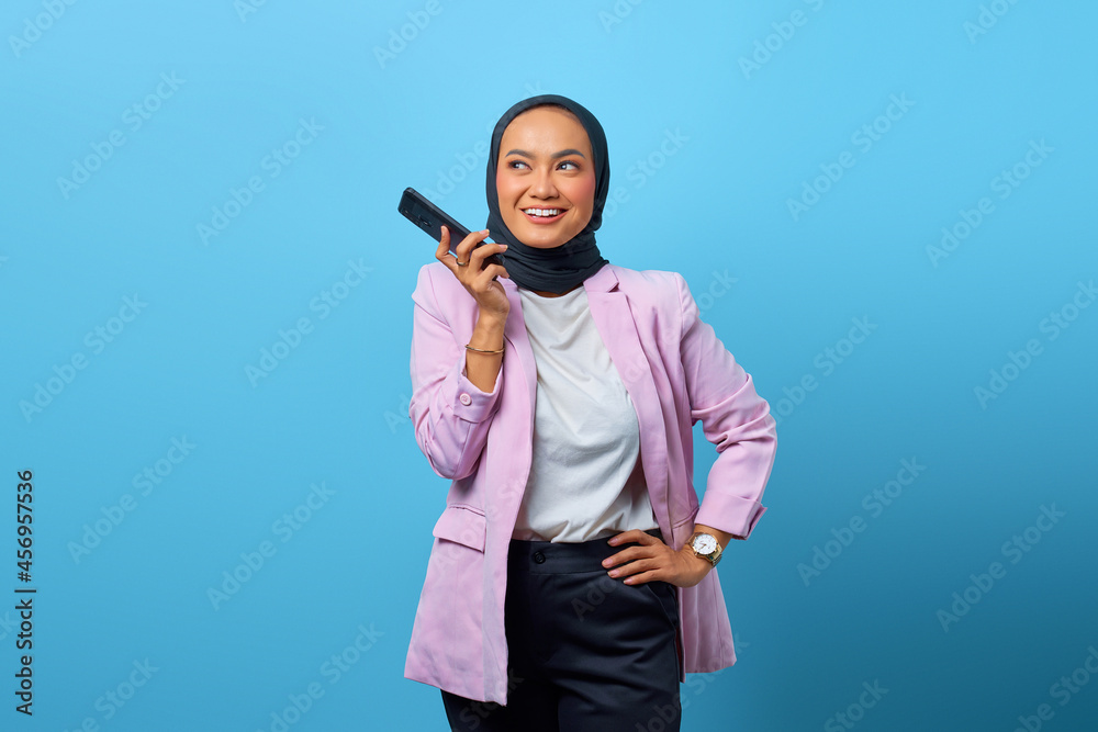 Portrait of cheerful Asian woman using mobile phone over blue background Portrait of cheerful Asian woman using mobile phone over blue background