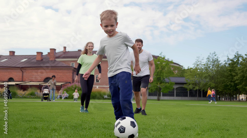 Cheerful family in sportswear playing soccer outdoors
