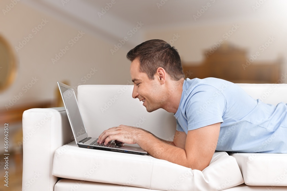 Smiling young adult freelance business man using laptop Smiling young adult freelance business man using laptop