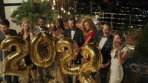 Group of beautiful people carrying gold colored numbers celebrating New Year 