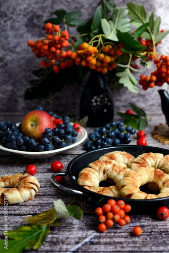 Beautiful vertical composition. Apples, grapes, rowan branches and homemade cakes with apples on a dark wooden background