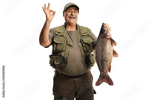 Happy mature fisherman holding a carp fish and gesturing good photo