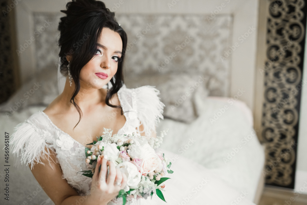 Naklejka premium Beautiful bride wearing fashion wedding dress with feathers with luxury delight make-up and hairstyle, studio indoor photo shoot