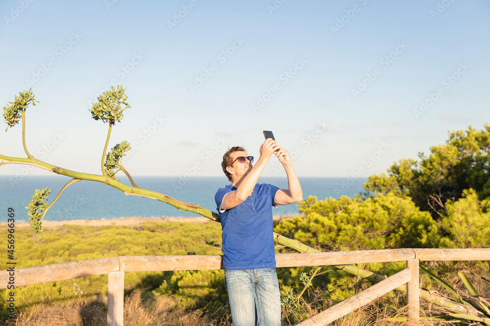 mature man taking selfies with mediterranean sea view and green vegetation. Alicante, spain mature man taking selfies with mediterranean sea view and green vegetation. Alicante, spain