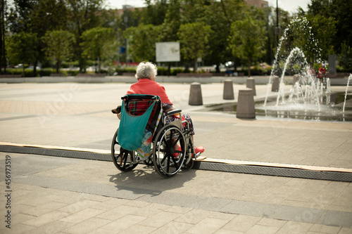 Disabled person in the square in a wheelchair. A person with disabilities in the city.