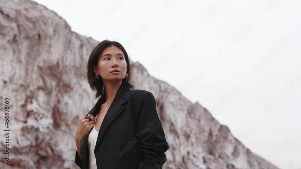 asian woman walking in a futuristic cosmos place across the mountains near water and white sand 