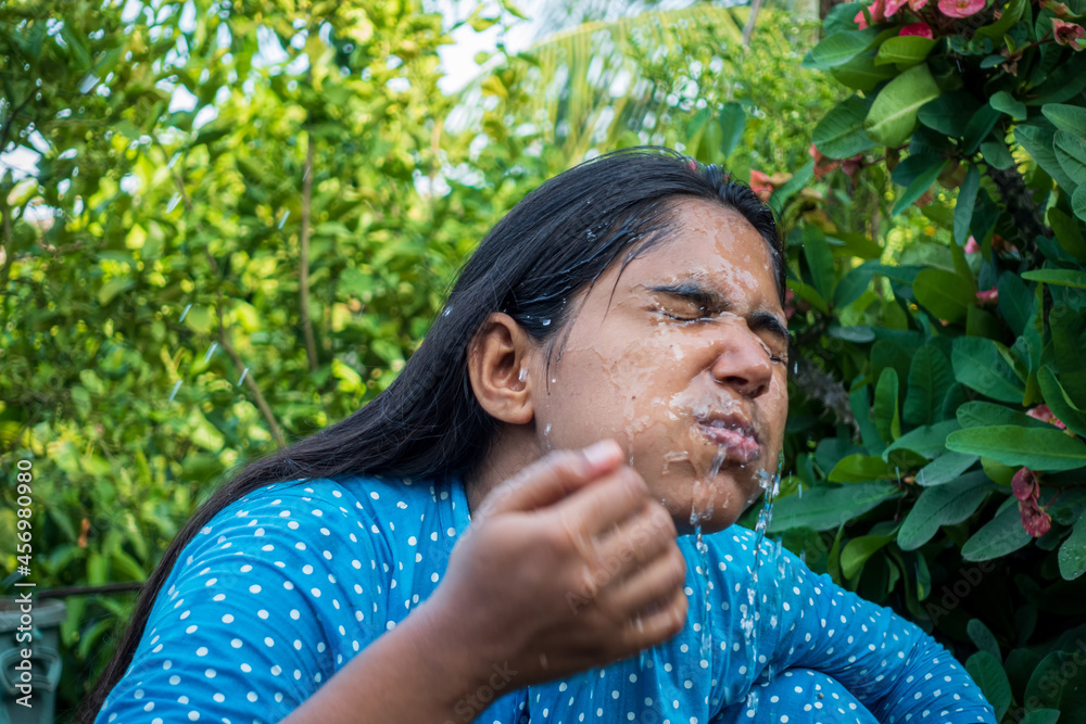 A woman splashes cold water on her face on a hot day. Closeup view of a young girl cleaning her face with water. Happy beautiful girl washes her face with pure water. A woman splashes cold water on her face on a hot day. Closeup view of a young girl cleaning her face with water. Happy beautiful girl washes her face with pure water.