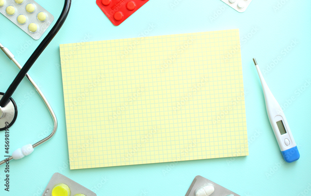 Yellow notebook that lies next to the stethoscope on a blue background Yellow notebook that lies next to the stethoscope on a blue background