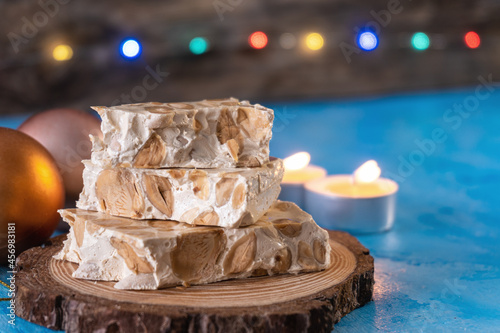 Turron from Alicante, typical Christmas sweet from Spain, with Christmas decoration, with a defocused background of colored lights