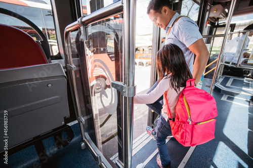 Tableau sur toile asian father taking his daughter to school by riding bus public transport