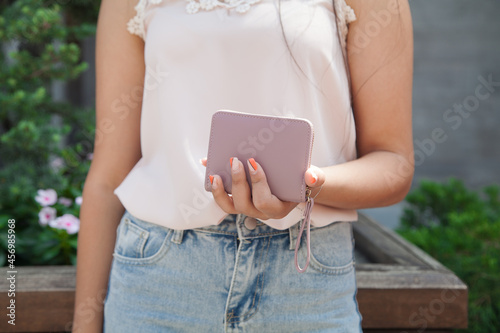 Woman standing on the street holding wallet.