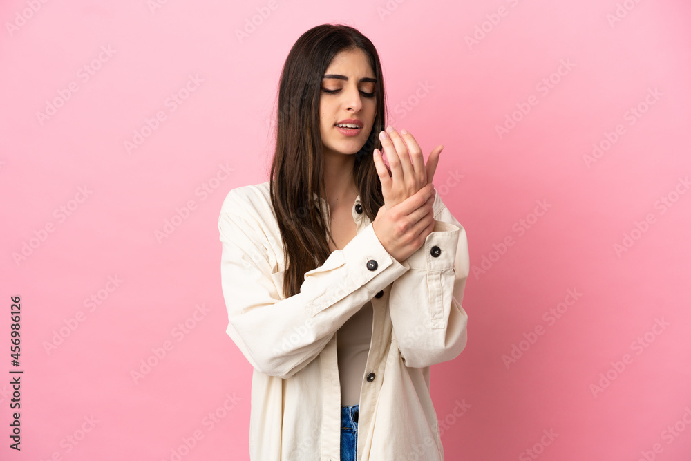 Young caucasian woman isolated on pink background suffering from pain in hands Young caucasian woman isolated on pink background suffering from pain in hands