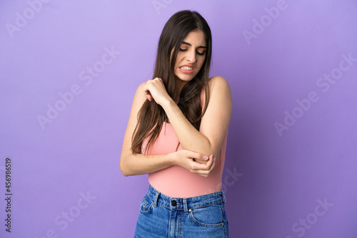 Young caucasian woman isolated on purple background with pain in elbow © luismolinero